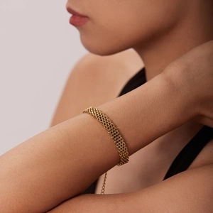 Gros plan d'un bracelet en maille d'acier inoxydable plaqué or 18k porté au poignet d'une femme