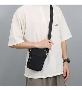 Detailed view of black nylon messenger bag with adjustable strap worn by model