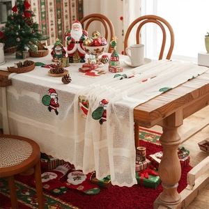 Christmas table runner with Santa embroidery and white lace on festive wooden table