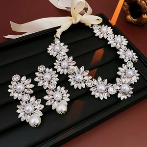 Detail of silver floral necklace and earring set with pearls and rhinestones on black tray
