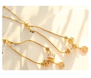 Detail of 18K gold plated snake chains with zircon stones and heart charms in close-up