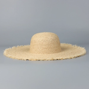 Détail d'un chapeau de soleil en raphia à large bord avec des bords effilochés chic