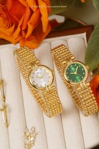 Detailed close-up of luxury gold-tone women's watches with green and white dials in gift box