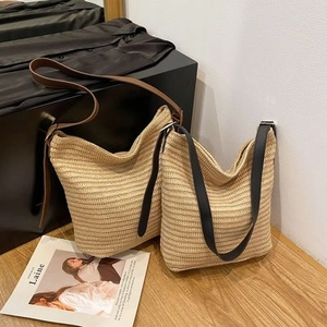 Vista detallada de bolsos de paja trenzada con correas de cuero marrón y negro