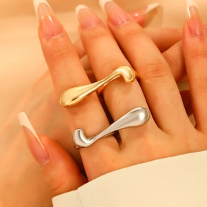 Dettaglio di anelli geometrici color oro e argento dal design minimalista fluido