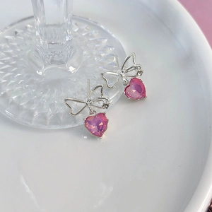 Makroaufnahme von Schleifen-Herz-Ohrringen mit rosa Kristallen und silbernem Metall