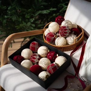 Close-up of red and white flocked Christmas ornaments with gold glitter in a gift box