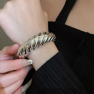 Macro detail of polished silver irregular ribbed cuff bracelet on a model wrist