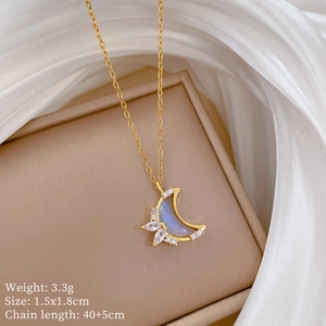 Detail of gold crescent moon necklace with blue stone and zircon on beige jewelry box