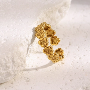 Macro detail of 18K gold-plated floral open ring resting on natural white stone base