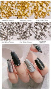 Detail of gold and silver pyramid metal nail studs in multiple sizes on black manicure