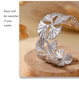 Detailed view of silver ginkgo leaf stainless steel cuff bracelet on wooden base