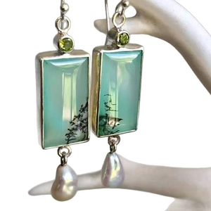 Vintage geometric earrings with green stones and baroque pearls on a white stand