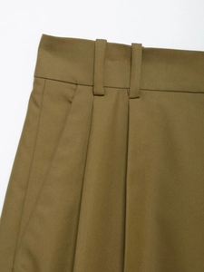 Detailed macro view of high-waisted olive green shorts featuring pleated front and belt loops