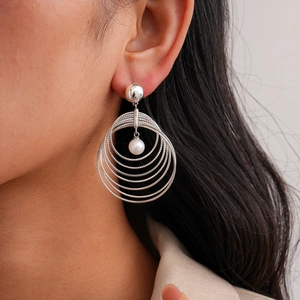 Close-up of silver geometric earring with five concentric rings and a central white pearl