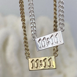 Close-up of dual-layer link necklace with 18K gold rectangular pendant and 11:11 engraving