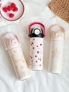 Three cute cartoon vacuum flasks with floral patterns on a cozy white fabric setting