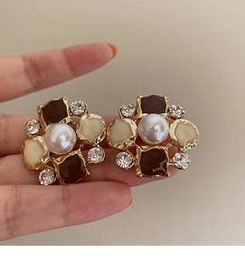 Close-up of vintage flower earrings with pearl, gold relief frame and colorful enamel