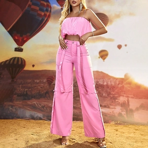 Dettaglio del crop top rosa a pieghe e dei pantaloni a gamba larga su modella al tramonto
