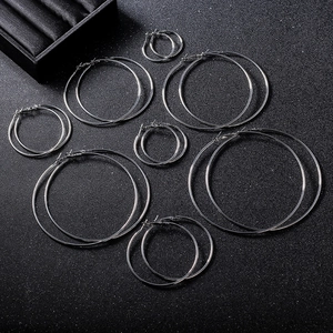 Flat lay of various sized silver hoop earrings set on dark textured surface
