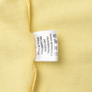 Detailed close-up of garment care label and stitching on yellow knitted fabric set