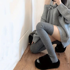 Close-up of grey knitted over-knee socks and sweater set with fine ribbed texture