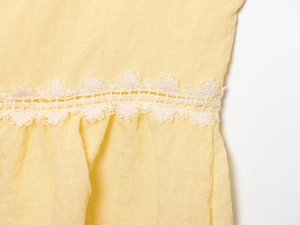 Close-up of yellow textured fabric with exquisite white lace embroidery details