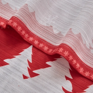 Detail of red Christmas tree print on white textured fabric with snowflake patterns
