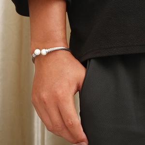 Detail of silver twisted wire cable cuff bracelet featuring two white pearl endpoints