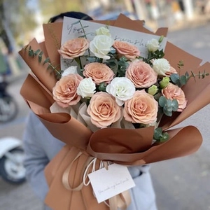 Close-up of champagne roses and white flowers wrapped in textured polka dot embossed paper