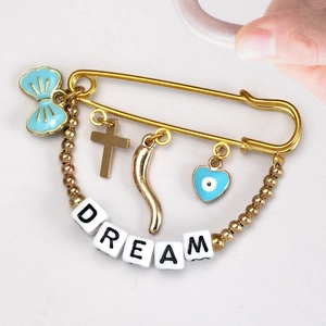 Detail of gold brooch with blue evil eye heart and Dream letter beads charms