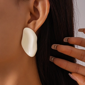 Close-up of a cream irregular geometric oval earring worn by a model in a studio