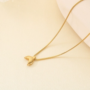 Detail of a golden fishtail pendant necklace with hammered texture on a pearl background