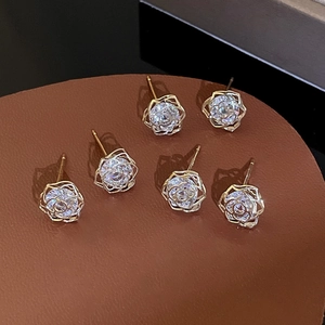 Macro detail of six hollow rose earrings with sparkling zircon on dark leather