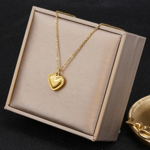 Minimalist gold heart pendant necklace with beaded edges on a beige jewelry gift box