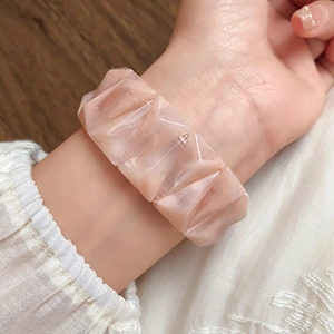 Macro detail of geometric peach resin bracelet with marble texture on female wrist