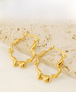 Détail de boucles d'oreilles ondulées irrégulières plaquées or 18 carats texture liquide