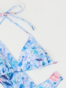 Flat lay of blue floral halter bikini set with abstract print on light grey background