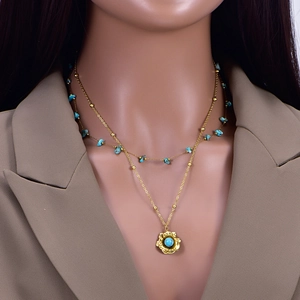 Collana doppia dorata con frammenti di turchese e pendente a fiore su modella