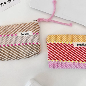 Detail of colorful woven striped cosmetic pouches with zippers and decorative lanyards