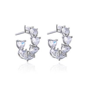 Macro shot of silver C-shaped hoop earrings with heart-cut white zircon insets