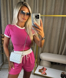 Detail view of pink ribbed knit two-piece set featuring white trim on crop top and shorts