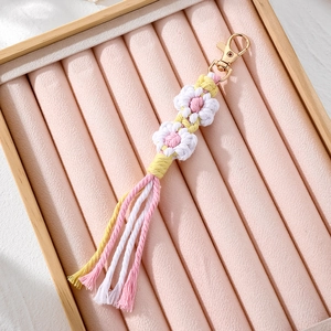 Detailed view of handmade woven daisy flower keychain with soft cotton tassels and gold clasp