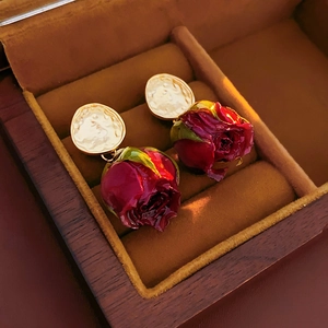 Vue macro de boucles d'oreilles rose 3D rouge bordeaux avec base dorée texturée