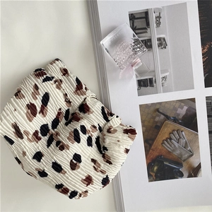 Detail of ruched chiffon fabric with brown leopard spots on an ivory cosmetic bag