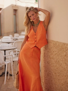 Outdoor shot of orange linen two-piece set featuring V-neck vest and A-line maxi skirt