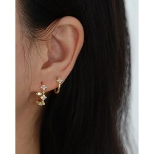 Detail view of gold clover earrings with sparkling clear crystals in a luxury set