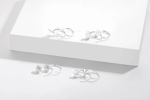 Detail shot of four pairs of sterling silver hoop earrings with butterfly and clover motifs