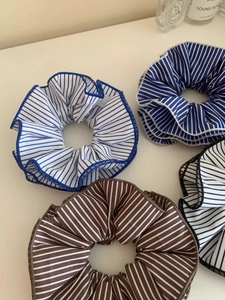 Detailed macro shot of blue and brown striped knit fabric scrunchies on white table