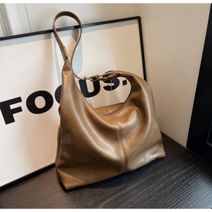 Detail of soft brown leather hobo bag texture on a dark wooden surface with a focus text